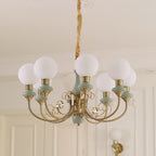 Sage-green Clérachic Brass Scrollwork Chandelier in the eight-light size, lit in front of tall panelled doors.