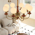 Clérachic Brass Scrollwork Chandelier in red-brown seen from above, eight lit globes over a pale sofa and tiled floor.