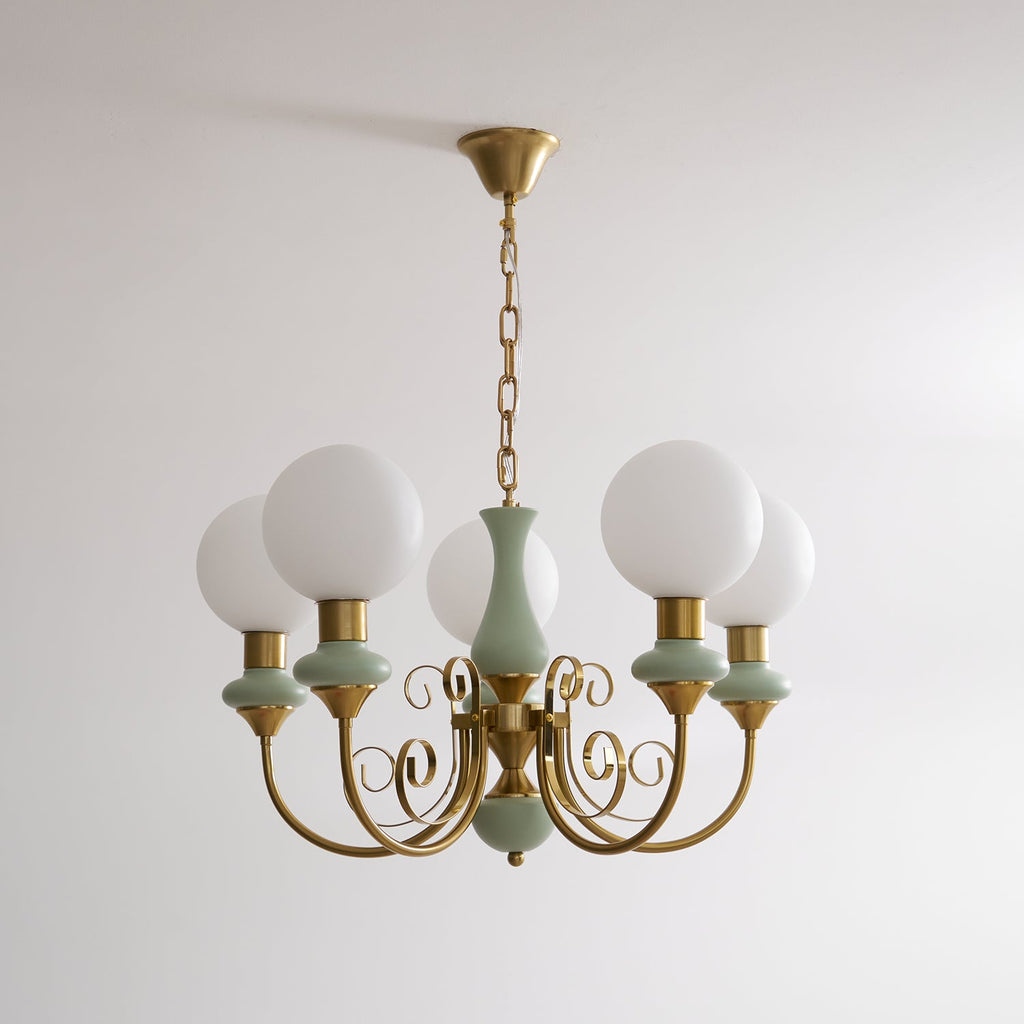 Sage-green Clérachic Brass Scrollwork Chandelier shown unlit on a brass chain against a plain white studio wall.