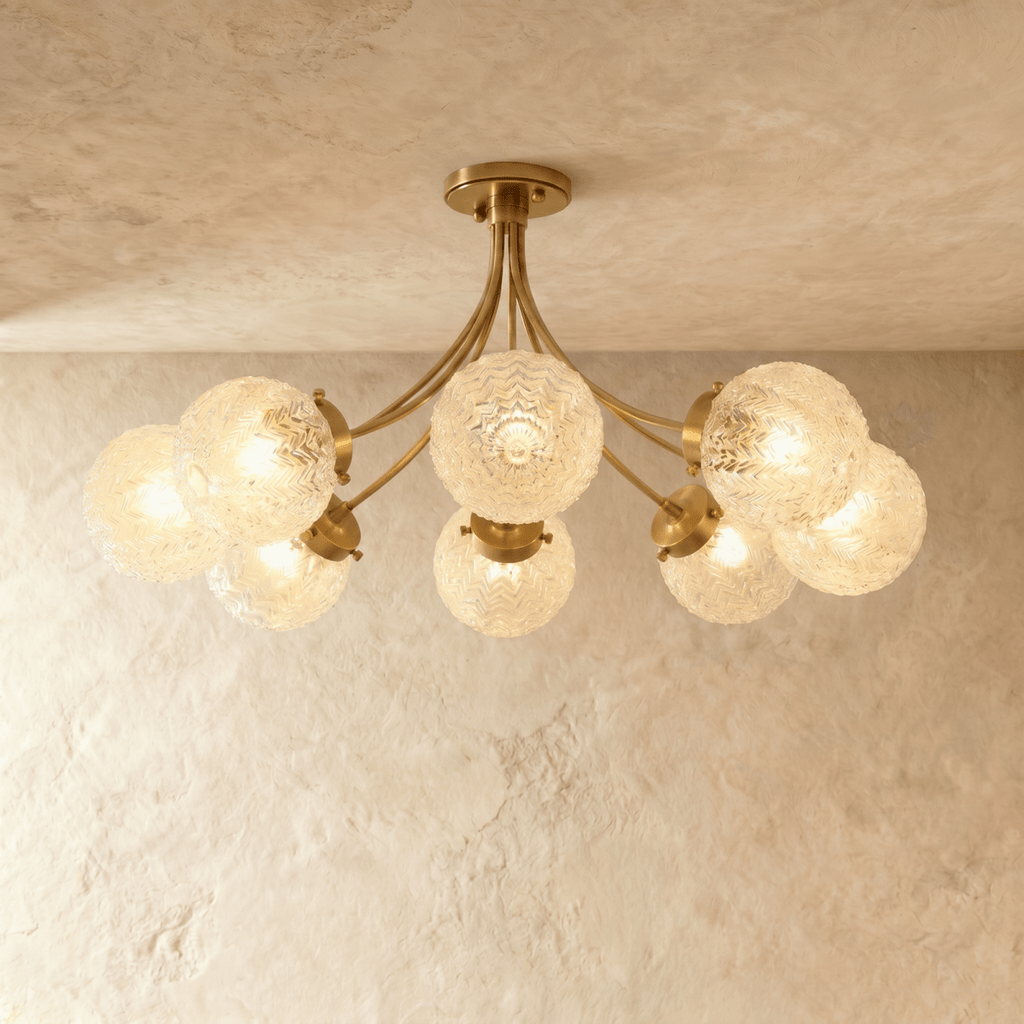 Clérachic eight-head semi-flush ceiling light with sweeping brass arms and ribbed glass globes on a limewash ceiling.