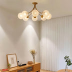 Clérachic eight-head brass ceiling light with frosted textured globes in a living room with a light oak sideboard and curtains.