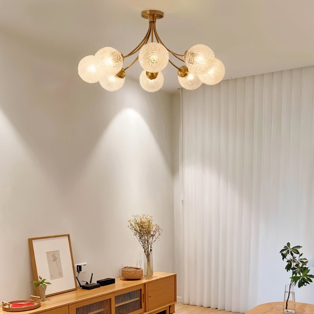 Clérachic eight-head brass ceiling light with frosted textured globes in a living room with a light oak sideboard and curtains.