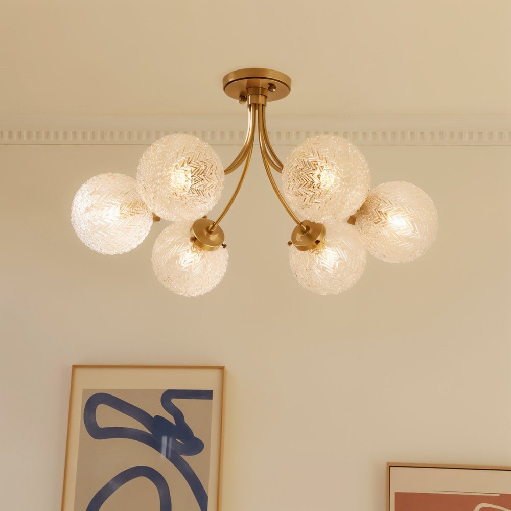 Clérachic six-head brass ceiling light with herringbone glass globes under a cornice, near framed abstract art.
