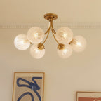 Clérachic six-head brass ceiling light with herringbone glass globes under a cornice, near framed abstract art.