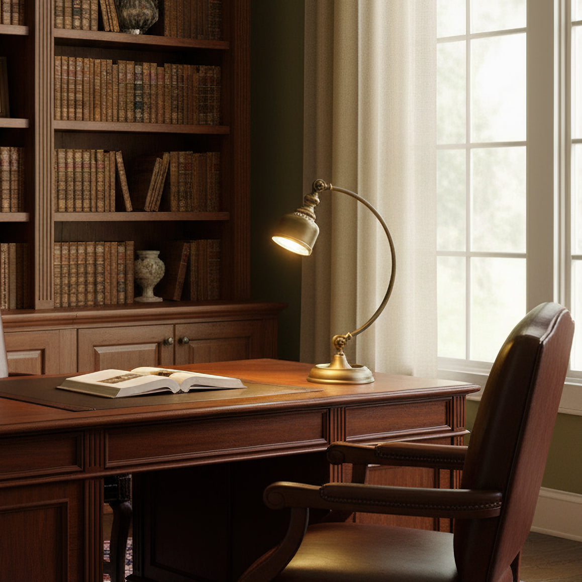 A Clérachic brass desk lamp glows on a dark wooden desk beside an open book, with a tall bookcase and window behind.