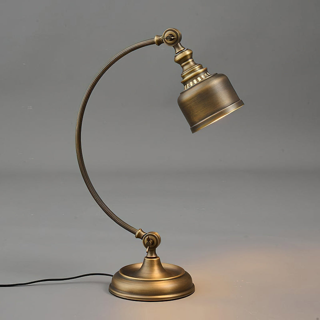 Full view of this Clérachic table lamp on a grey backdrop, its curved brass arm holding the shade over a round base with a black cord.