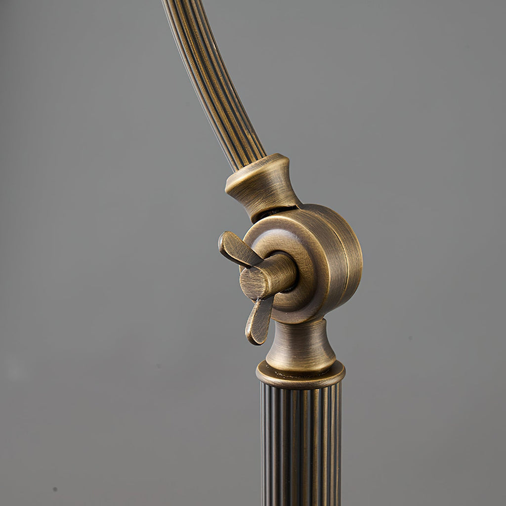 Close view of the lower arm joint on this Clérachic lamp, with a wing screw and a fluted brass stem, on a grey backdrop.