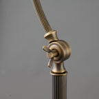 Close view of the lower arm joint on this Clérachic lamp, with a wing screw and a fluted brass stem, on a grey backdrop.