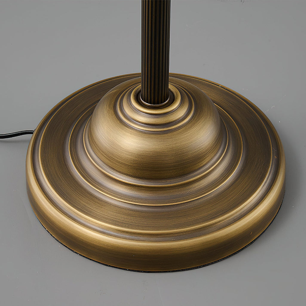 Close view of the stepped round brass base of this Clérachic table lamp, with the fluted stem rising from its centre.