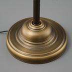 Close view of the stepped round brass base of this Clérachic table lamp, with the fluted stem rising from its centre.