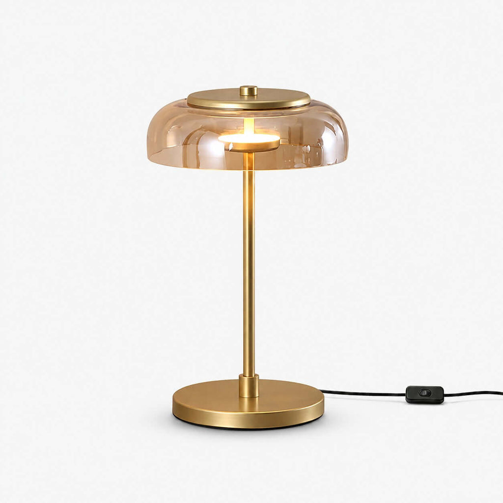Clérachic table lamp on a white backdrop, an amber glass dome over a slim brass stem and round base, with an in-line switch on the black cord.