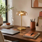 Clérachic table lamp with an amber dome lit on a walnut desk, beside a pen pot, notebooks and a closed laptop.