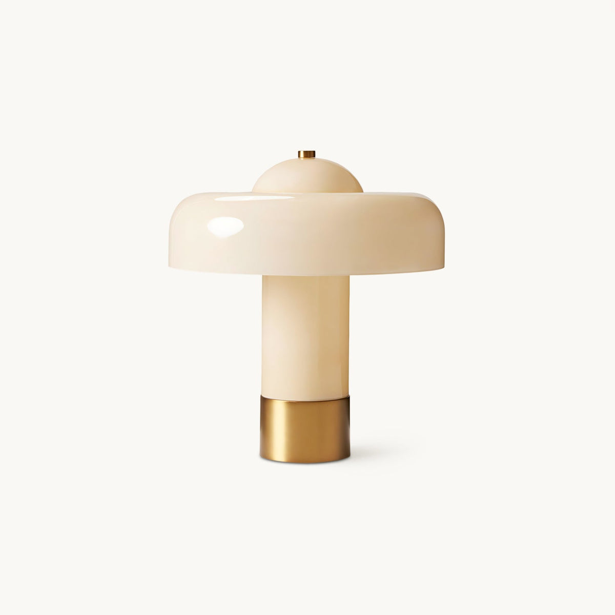 Table lamp from Clérachic with a glossy cream domed shade, a cream cylindrical stem and a brass base, on a plain white backdrop.