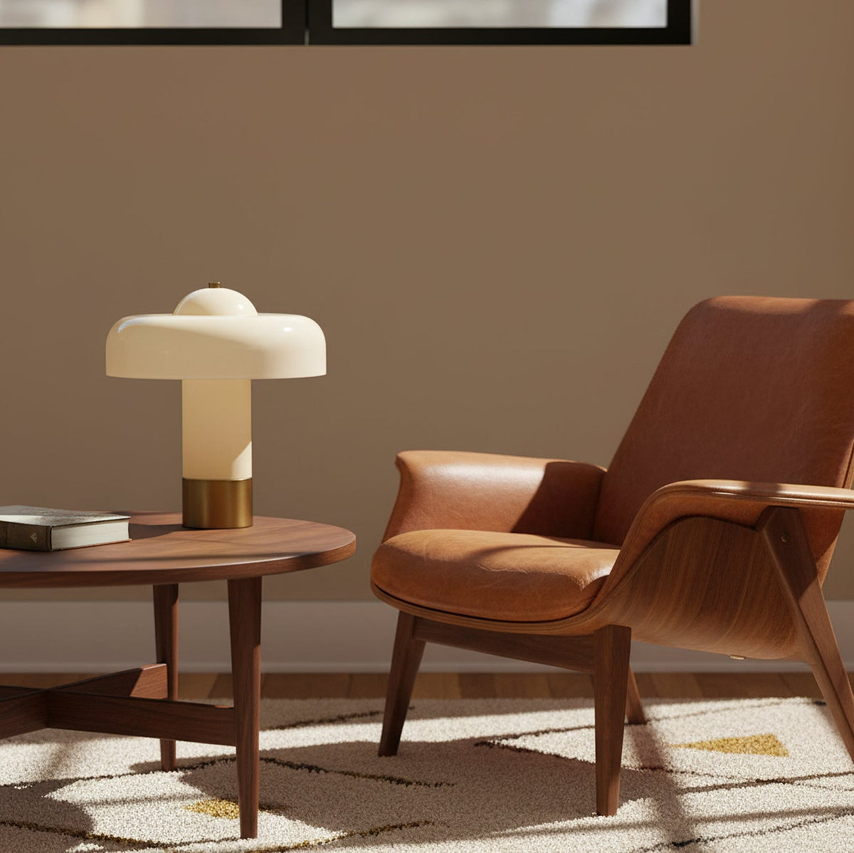 Beside a round walnut coffee table and a tan leather armchair, this Clérachic cream and brass lamp stands in warm afternoon light.