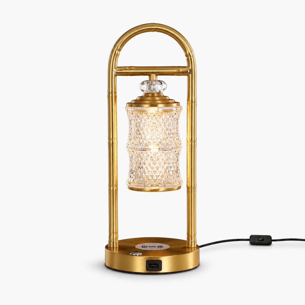 Brass Clérachic table lamp on a white backdrop, a faceted glass lantern hanging inside an arched frame above a round base.