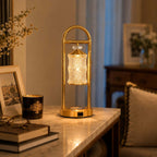 Lit Clérachic table lamp on a marble-topped desk, with a framed photograph and a stack of books in warm evening light.
