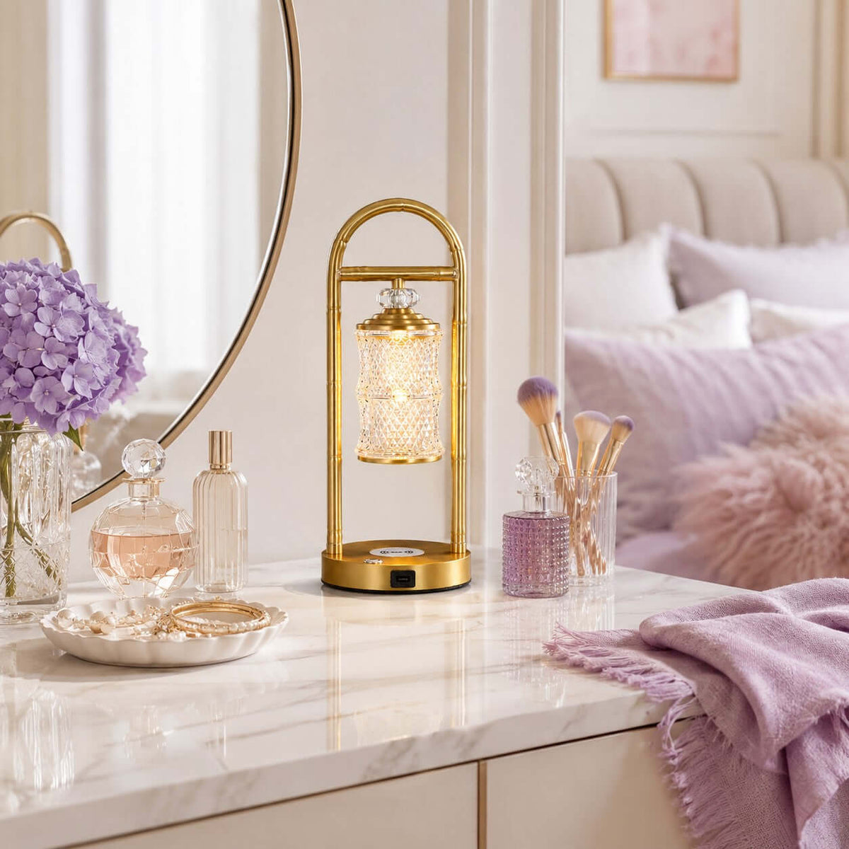 Clérachic table lamp on a white vanity with perfume bottles and make-up brushes, with lilac flowers and a pink throw nearby.