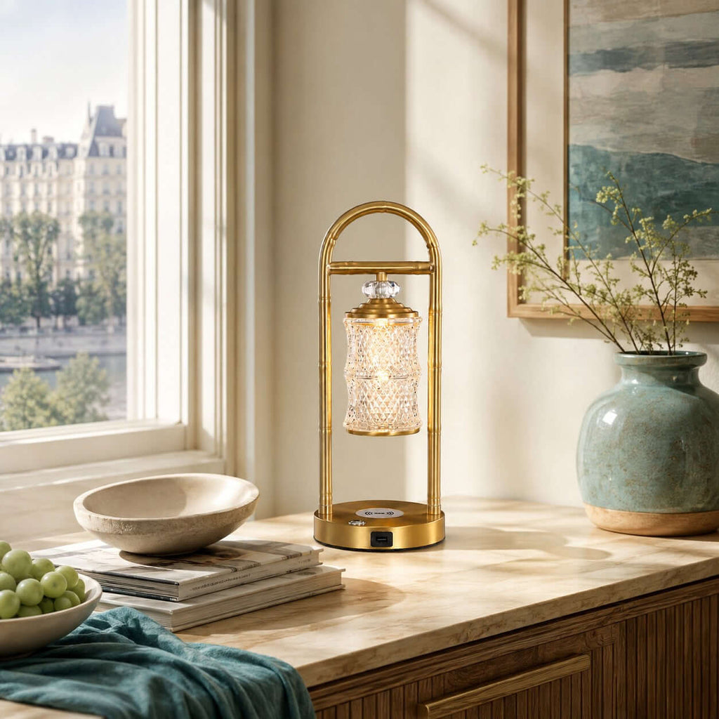 Clérachic table lamp on a wooden console by a window with a city view, beside a green vase and a stack of magazines.