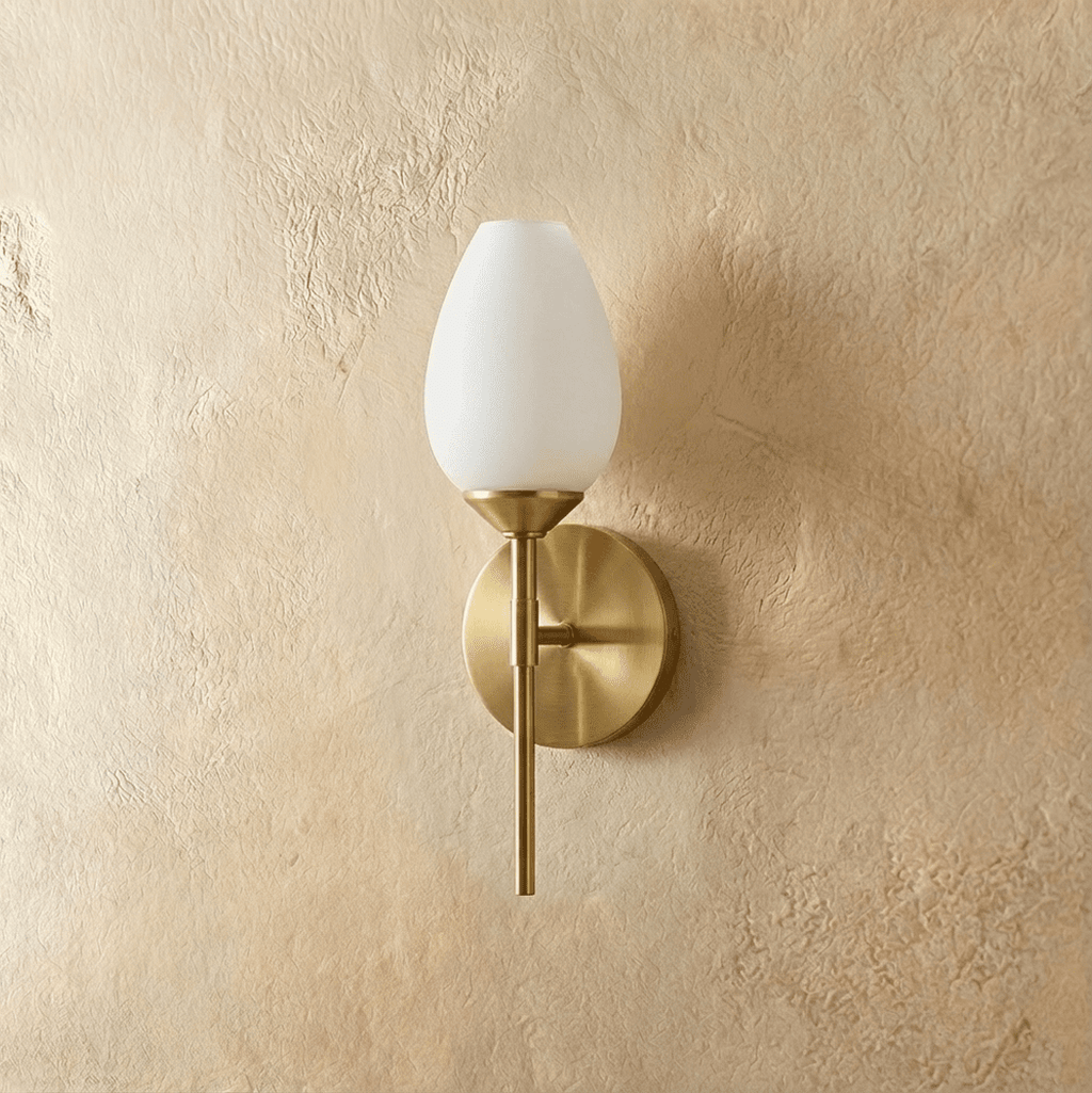 Clérachic brass wall lamp with a tulip-shaped frosted glass shade, switched off, on a round brushed backplate against plaster.