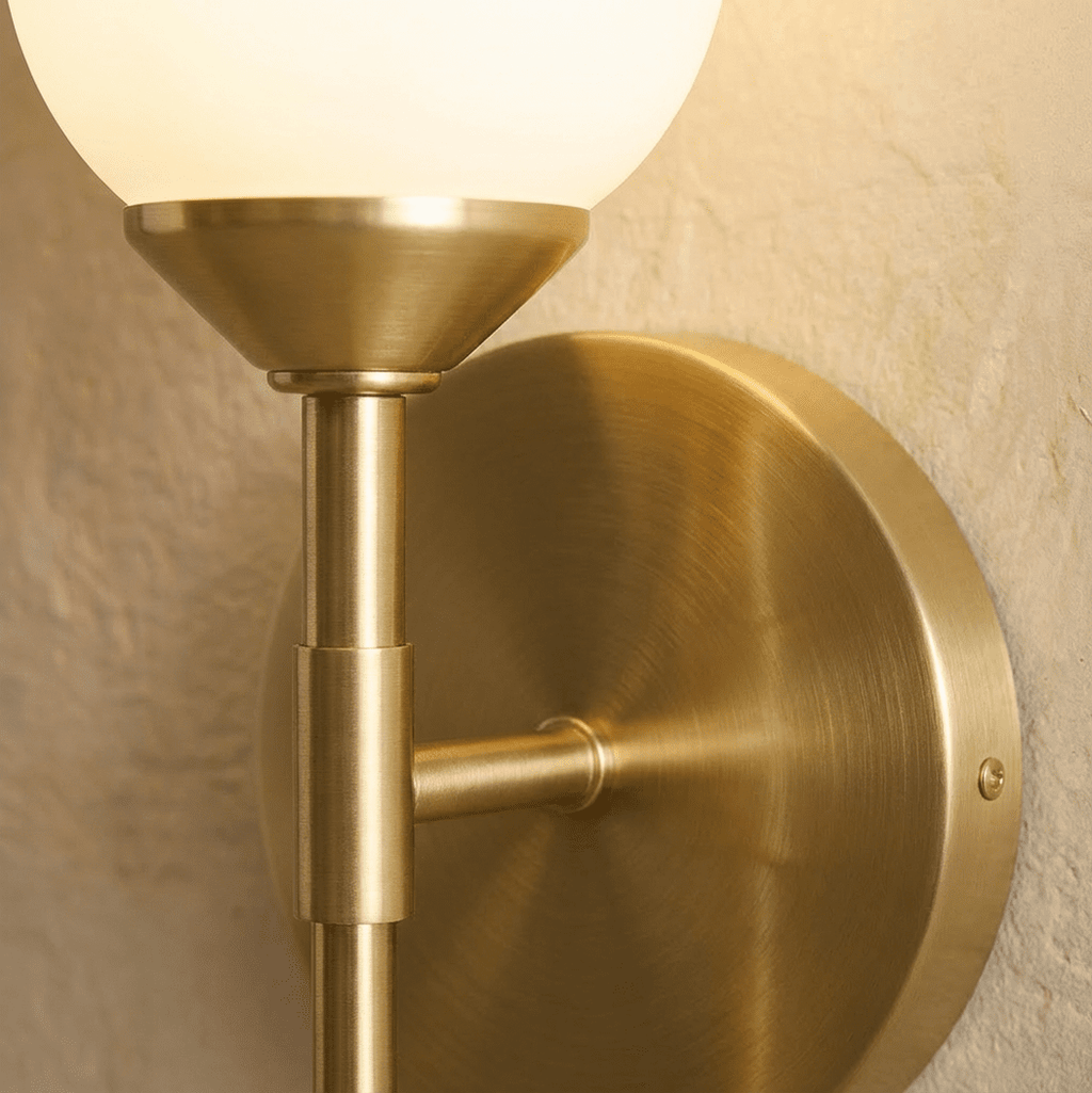 Clérachic brushed brass detail: the round backplate, side arm and stem joint beneath the frosted glass shade, with its fixing screw.