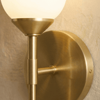 Clérachic brushed brass detail: the round backplate, side arm and stem joint beneath the frosted glass shade, with its fixing screw.
