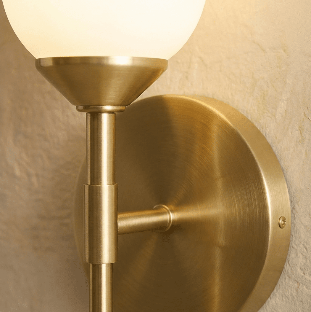 Clérachic brushed brass detail: the round backplate, side arm and stem joint beneath the frosted glass shade, with its fixing screw.