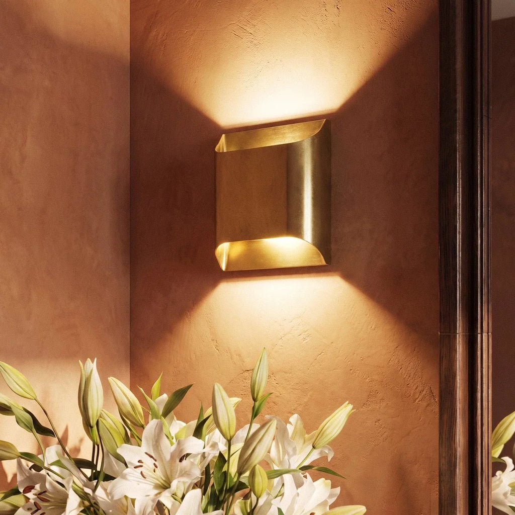 Close view of the Clérachic square brass wall light on a terracotta plaster wall, warm light above and below.