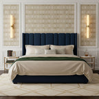 Above matching bedside tables, two tall alabaster tube lights glow in panels either side of a navy velvet headboard, from Clérachic.