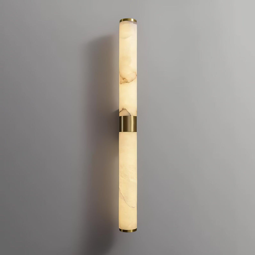 Close view of the veined alabaster of this Clérachic wall light, with its brass band and end caps against a grey wall.