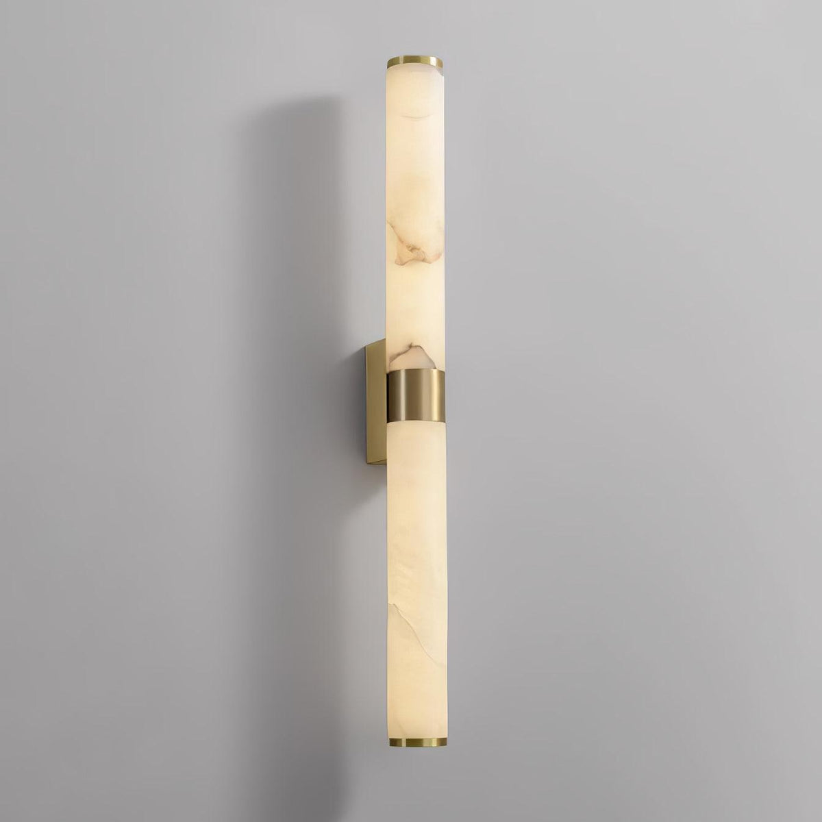 The brass wall plate behind the band is visible on this Clérachic alabaster tube light, against a pale grey wall.