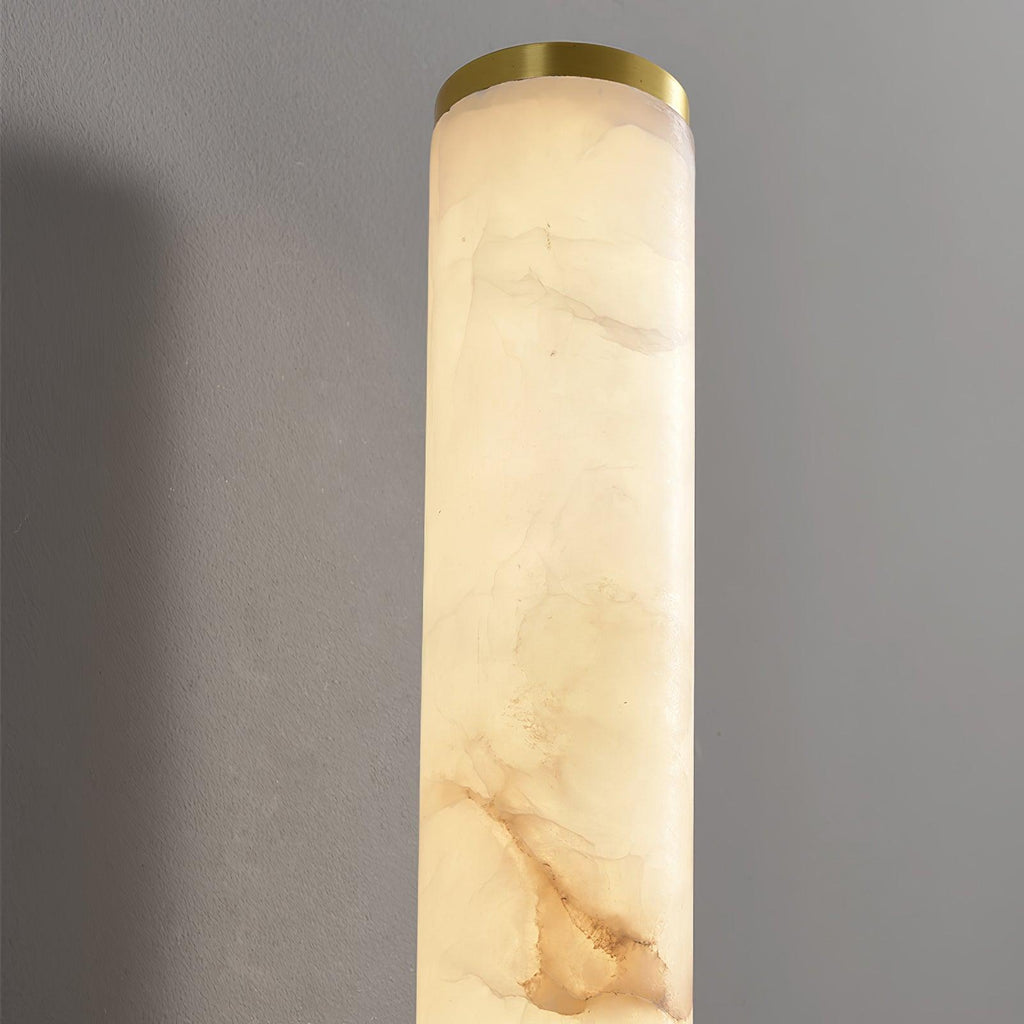 Close view of the top of a Clérachic alabaster tube, with its soft cream and tan veining and a thin brass end cap.