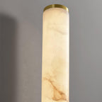 Close view of the top of a Clérachic alabaster tube, with its soft cream and tan veining and a thin brass end cap.