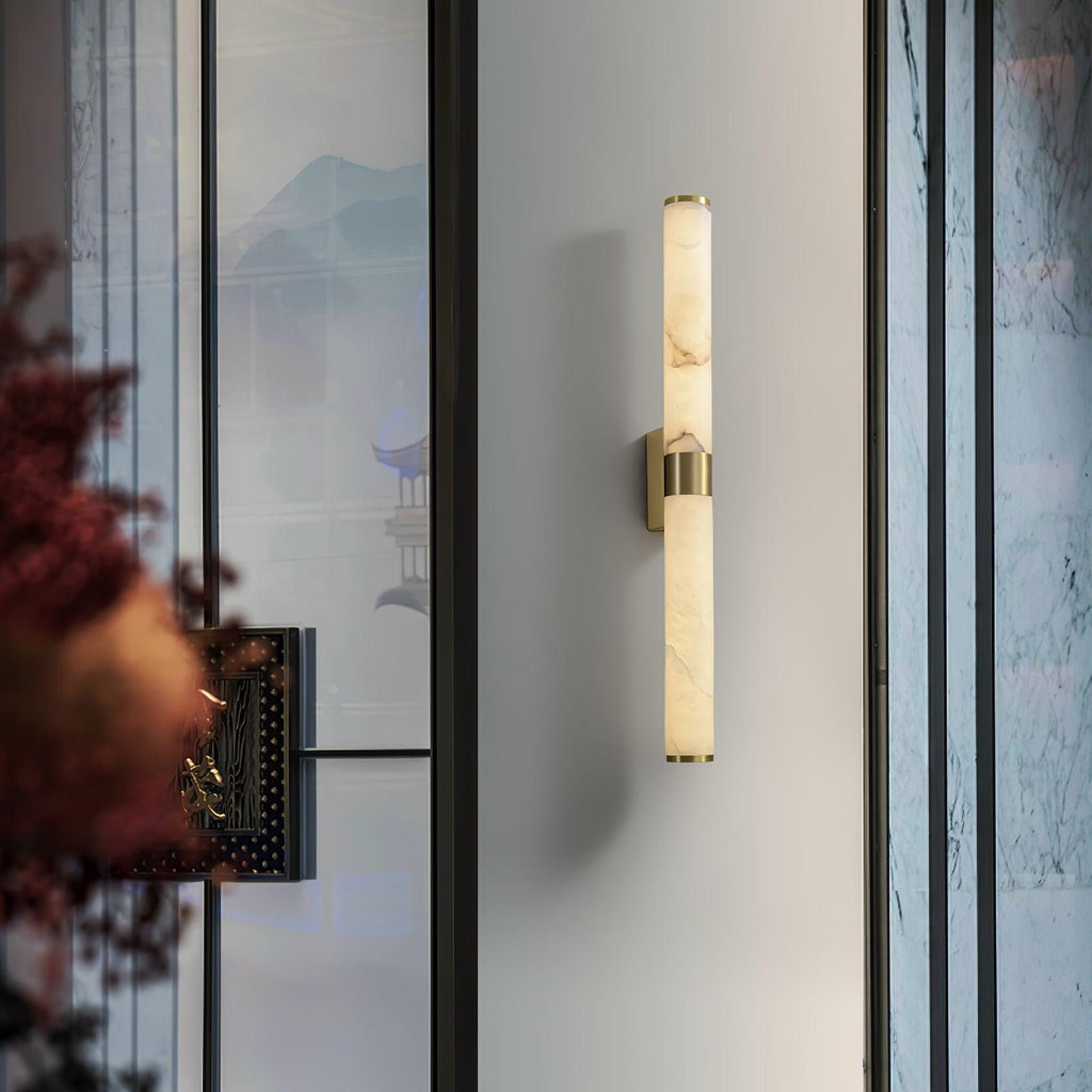 A distant view of this Clérachic alabaster tube light on a pale wall beside a glass screen and a red-leaved branch.