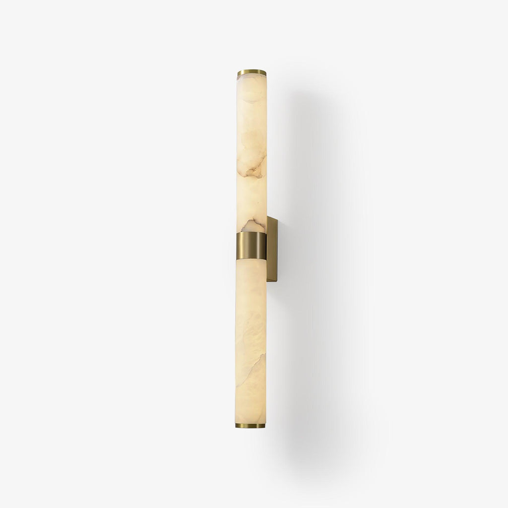 A veined alabaster tube wall light with a brass band and plate, on a soft white background with a faint shadow, from Clérachic.