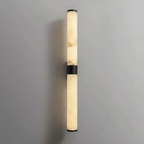 A black-banded alabaster tube wall light with black end caps on a pale grey wall, switched off, from Clérachic.