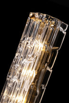 Close view of the clear, rippled glass of this Clérachic wall light, with the gold backplate and bulbs glowing inside, on black.