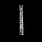 Switched-off Clérachic wall light on black, a longer model with a clear faceted glass cylinder and gold fittings.