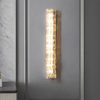 Large view of a Clérachic wall light lit against a grey panelled wall, with a marble-effect wall at the left.