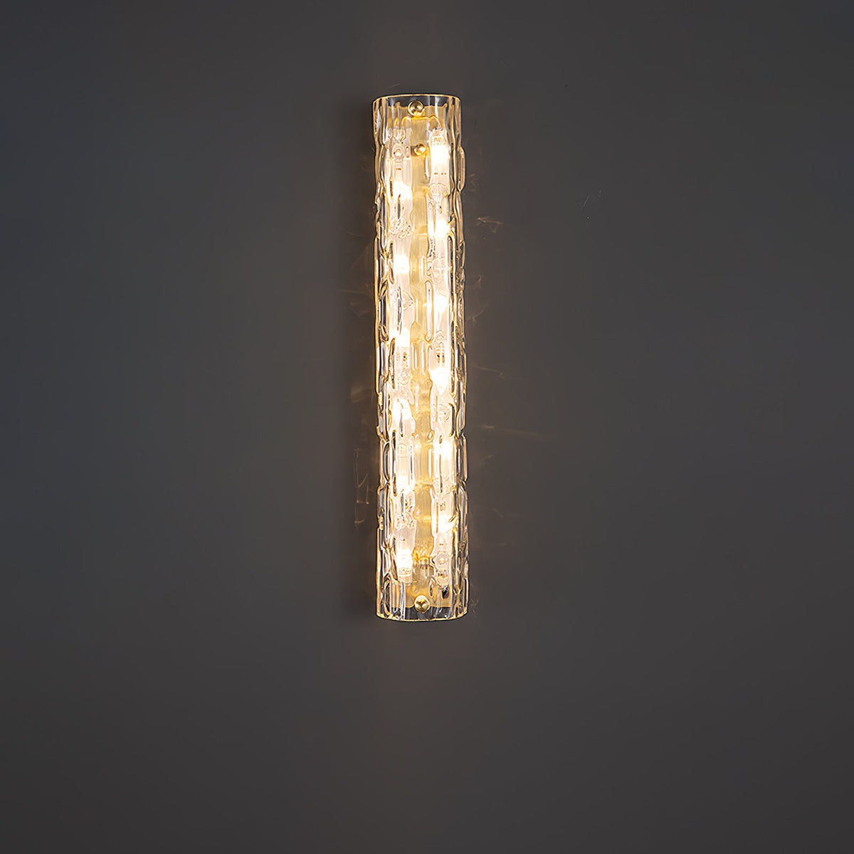 Clérachic glass wall light lit against a plain dark grey wall, its warm bulbs showing through the textured shade.