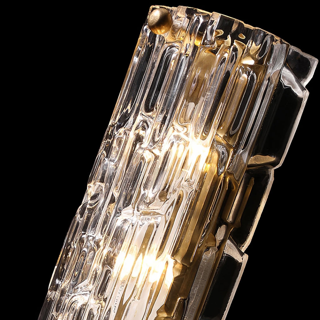 Close view of the rippled clear glass and gold fixing of this Clérachic wall light, lit from within, on black.