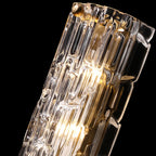 Close view of the rippled clear glass and gold fixing of this Clérachic wall light, lit from within, on black.