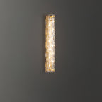 Lit Clérachic wall light on a dark grey wall, with its warm light showing through the textured glass.