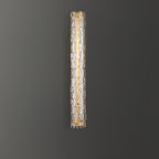 A Clérachic wall light with clear glass and a gold backplate, shown on a dark grey wall.