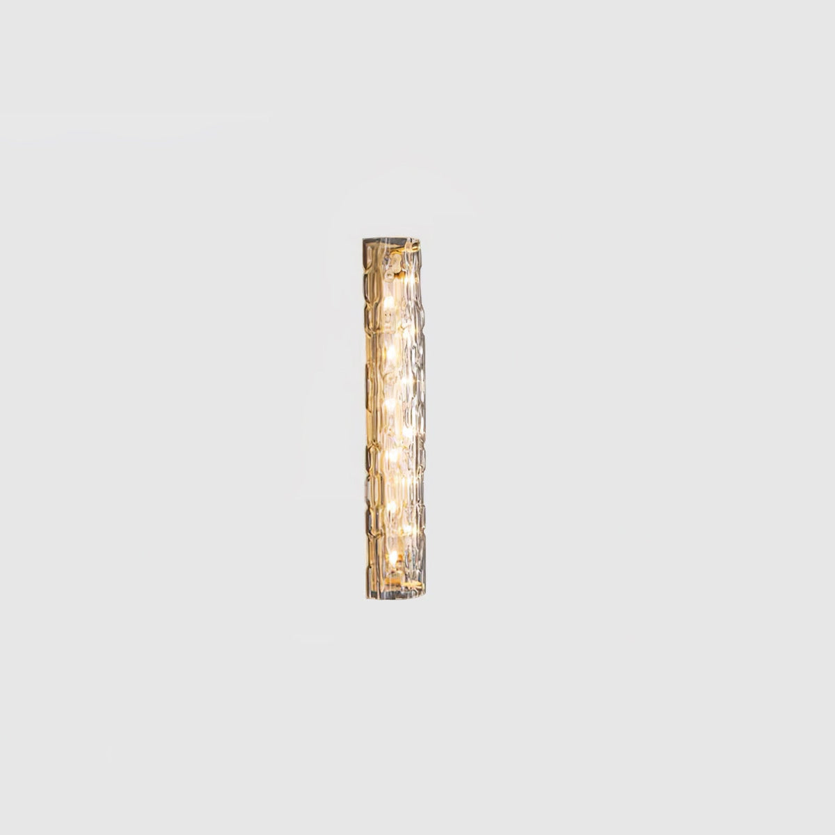 Small Clérachic glass wall light lit on a pale grey backdrop, its LEDs glowing behind the clear shade.