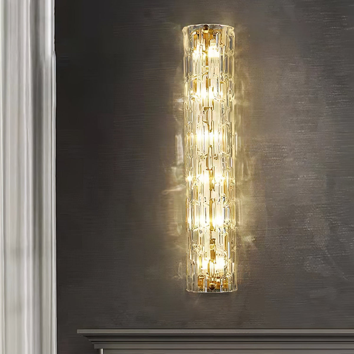 Close front view of a Clérachic wall light lit with bright bulbs on a dark grey wall, a sheer curtain at its left.