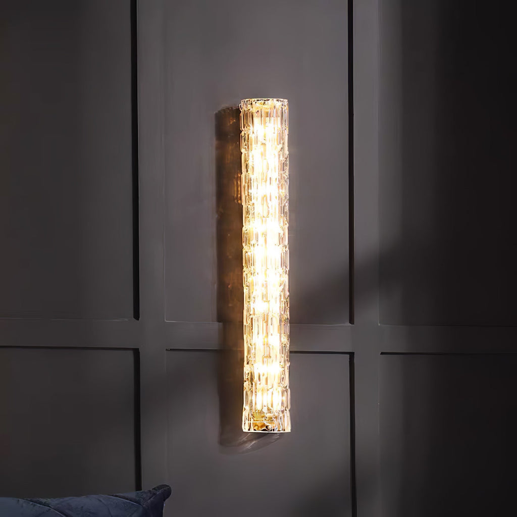 Clérachic wall light lit on a dark panelled wall, with the edge of a blue cushion at the bottom.