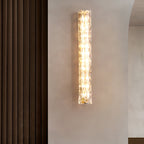 Clérachic glass wall light lit on a plaster wall beside a brown ribbed curtain.
