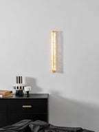 Clérachic wall light glowing softly above a black chest of drawers with brass pulls and a striped vase.