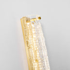 Close view of the top of this Clérachic wall light, with brass screws, gold backplate and rippled glass lit from inside.