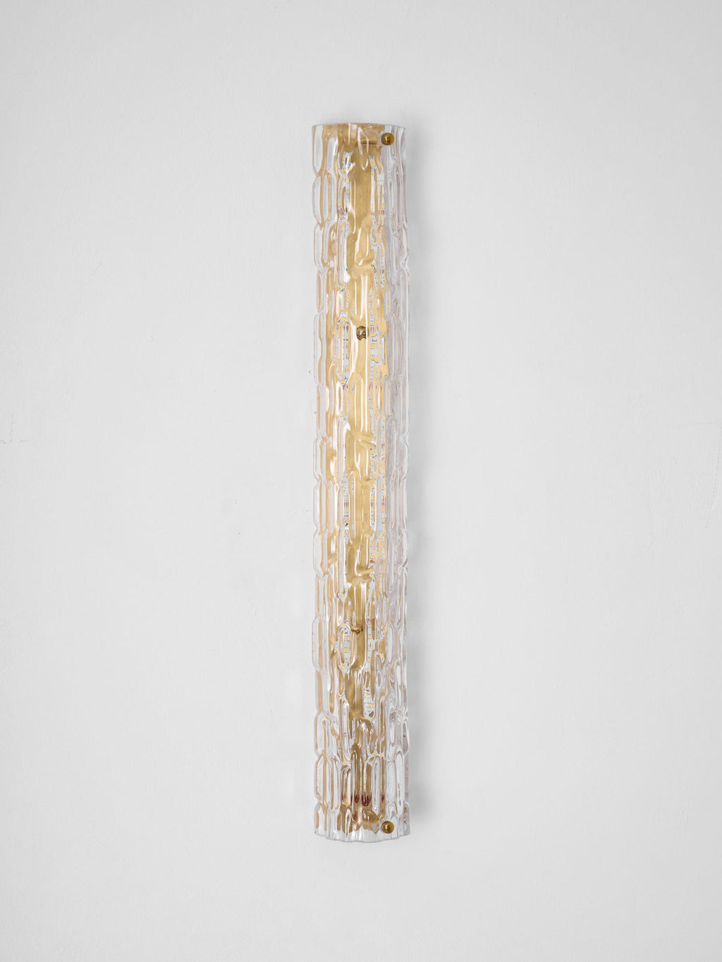 Full-length view of a Clérachic wall light on a pale wall, the clear rippled glass over a gold backplate with brass screws.